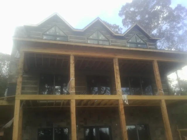 Dormers and porch framing on a large log home under construction — Roof Coating work by our crew in Brush Valley