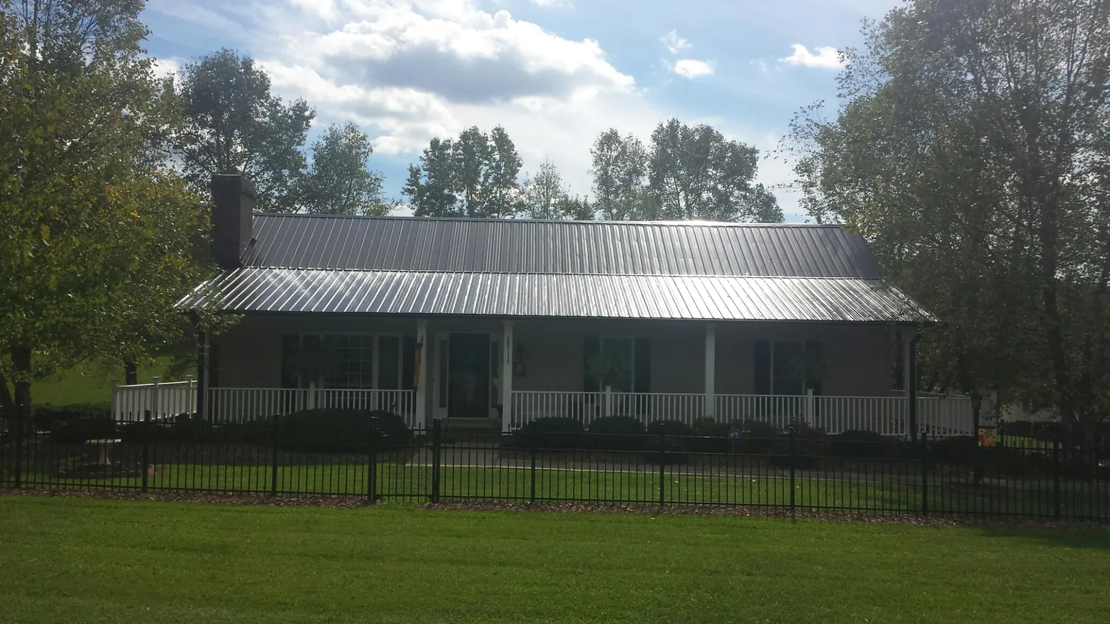 Gray metal roof on a brick ranch with a full width front porch — Gutter Guard Installation work by our crew in Brush Valley
