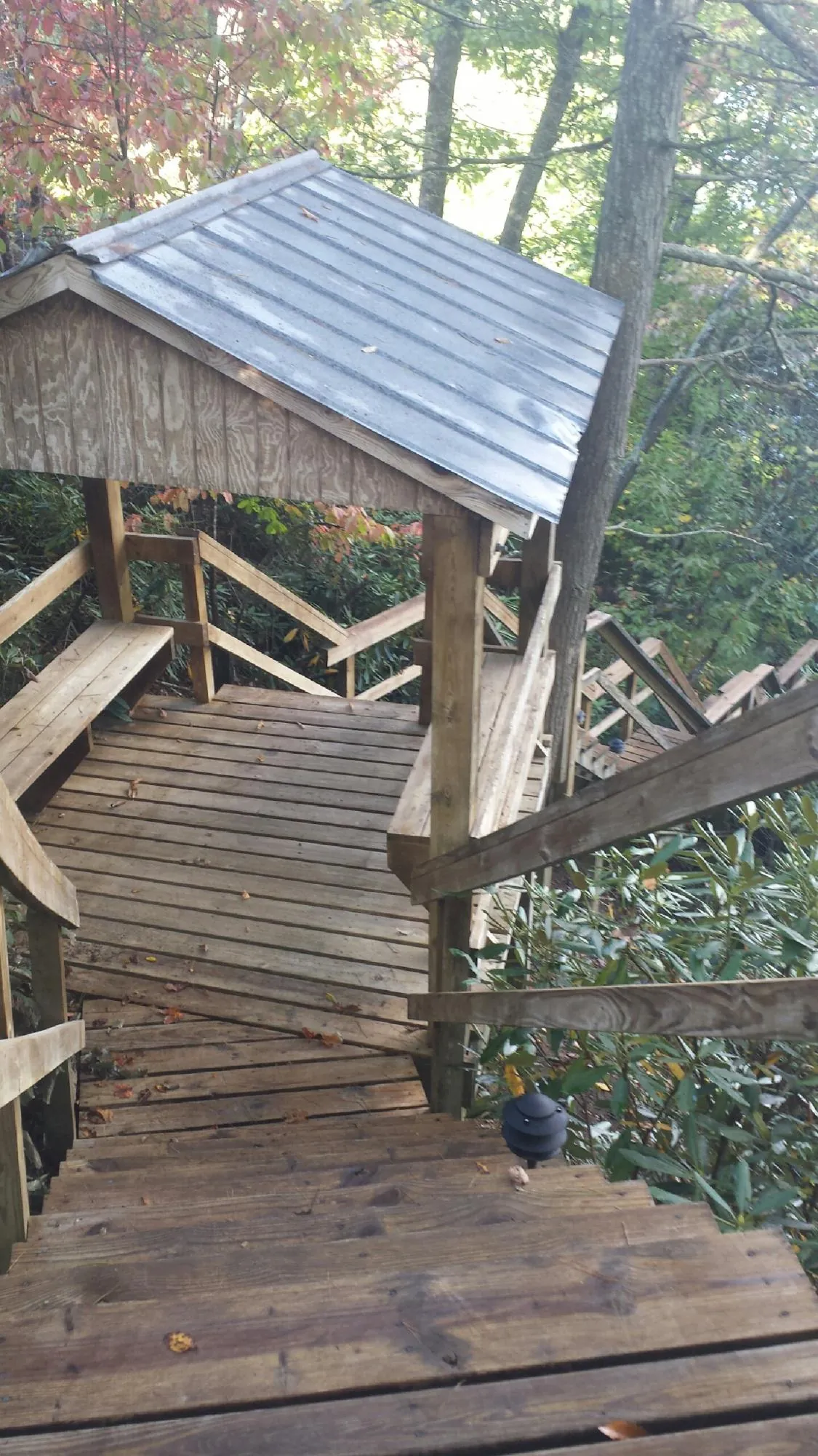 Metal roofed shelter over wooden steps on a wooded walkway — Skylight Repair & Installation work by our crew in Brush Valley