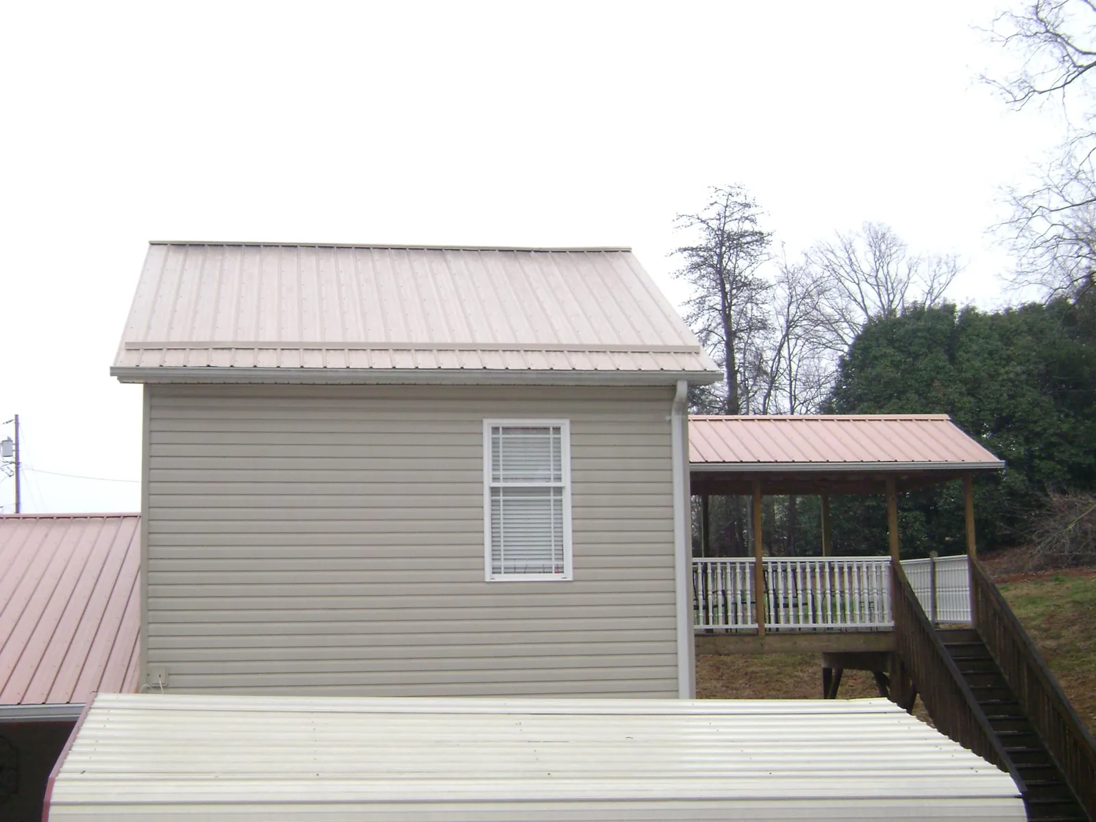 Tan metal roofs on a two story addition and attached porch, from a Roof Replacement job in Brush Valley