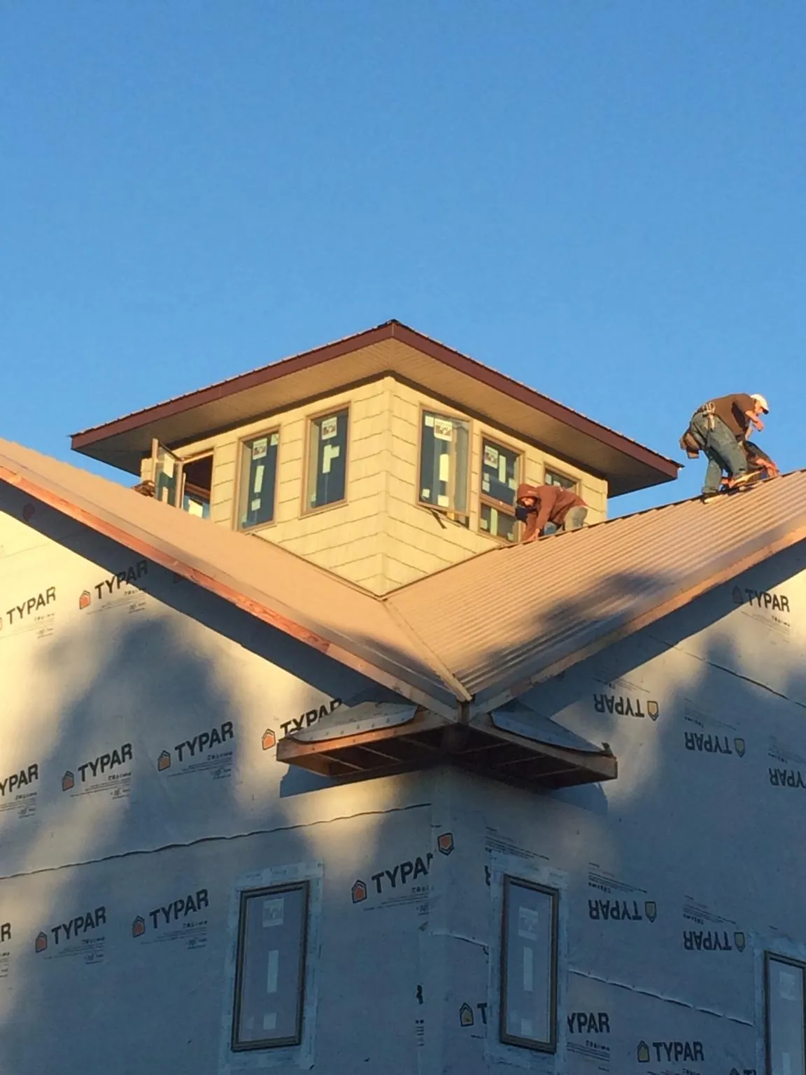 Roofers working around a rooftop cupola on a new metal roof at sunset — Roof Waterproofing in Brush Valley by Roofing Brothers